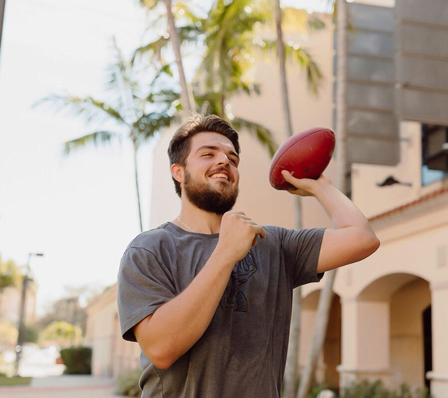 physical 教育 student throws a football on campus.